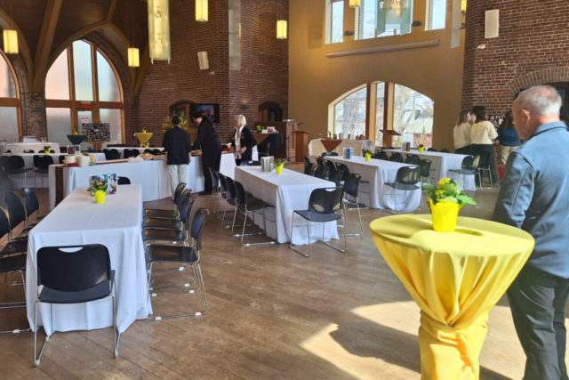 Reception-style event setup with cocktail table and seating in a large open hall